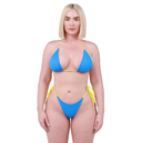 A blonde model wearing a bright blue string bikini with yellow trim and side-tie details, photographed against a plain white studio background.