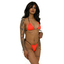 Woman wearing a bright orange bikini with black strings on a white background, sideview